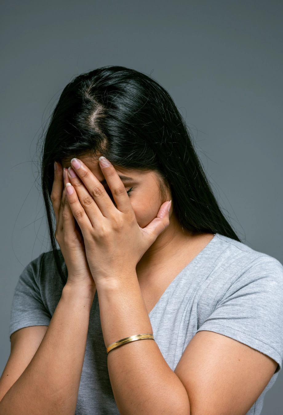 Mulher com as mãos no rosto ao perceber que repete padrões e não sabe de onde isso vem